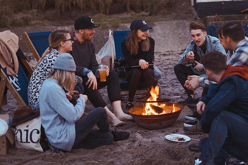 students happily chatting around a camp fire